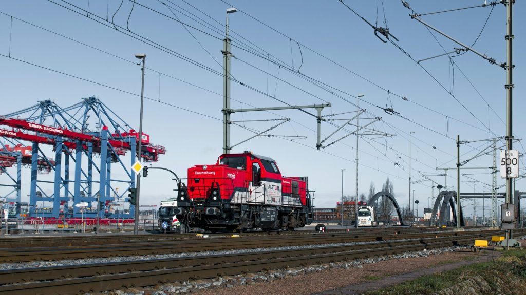 A red train moves near a harbor.